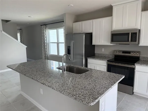 a kitchen with stainless steel appliances granite countertop a sink stove and microwave