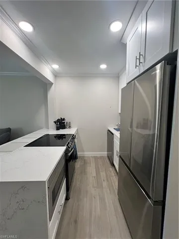 a kitchen with granite countertop a refrigerator a sink and wooden floor