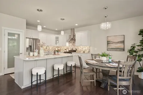 a kitchen with kitchen island granite countertop a dining table chairs and wooden floor