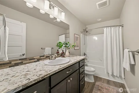a bathroom with a granite countertop sink a toilet a mirror and shower
