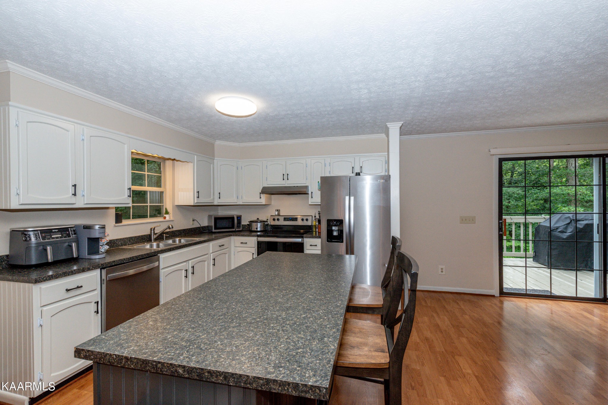 125 Lakeview Estates Road Vonore, TN 37885 - Photo 18 of 46 a kitchen with stainless steel appliances granite countertop a stove a refrigerator a sink a dining table and chairs with wooden floor