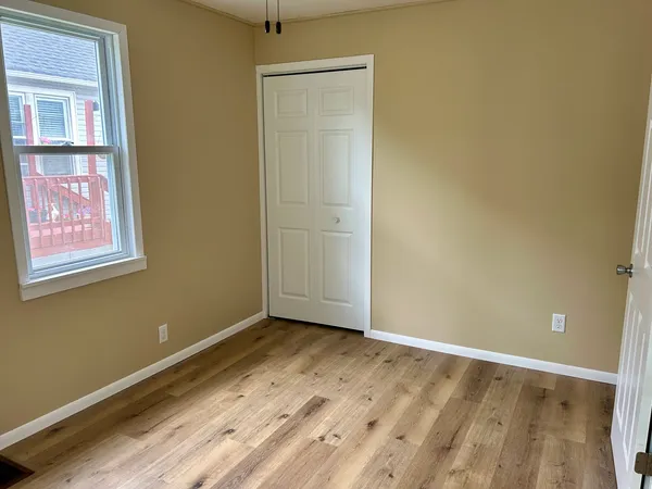 a view of an empty room with window and wooden floor