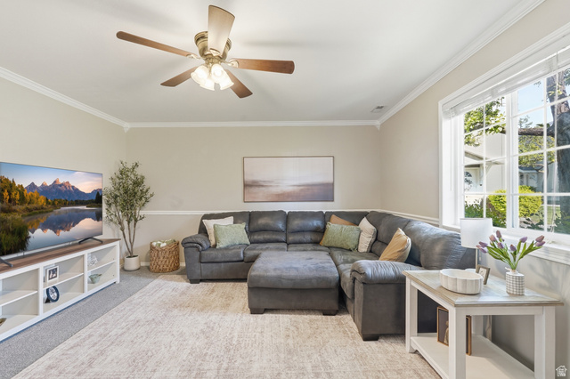 99 Penhurst Place Logan, UT 84341 - Photo 6 of 34 Spacious living area featuring light-toned walls, crown molding, a ceiling fan with integrated lighting, and a large multi-pane window