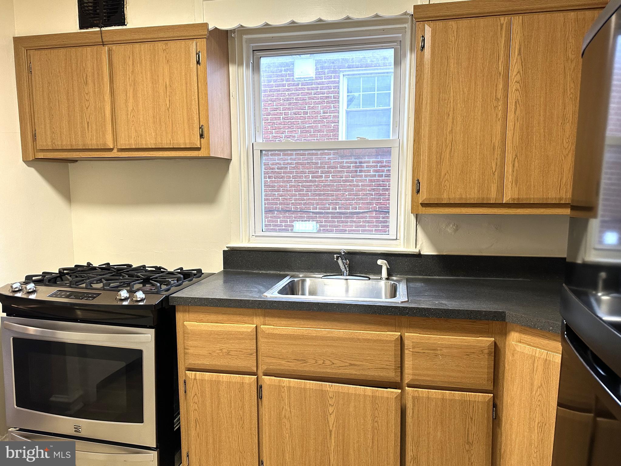 4934 Wynnefield Avenue, Unit 2 Philadelphia, PA 19131 - Photo 7 of 26 a kitchen with granite countertop cabinets stainless steel appliances and a window
