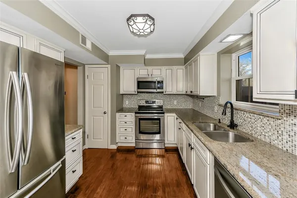 a kitchen with granite countertop a refrigerator stove and sink