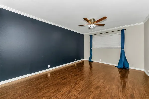 a view of an empty room with window and wooden floor