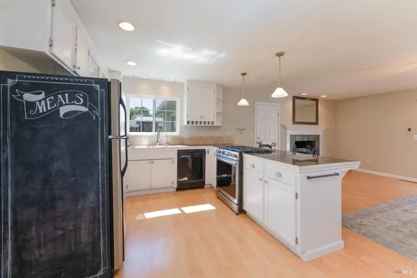 a kitchen with stainless steel appliances kitchen island granite countertop a refrigerator a stove a sink dishwasher with a dining table and chairs