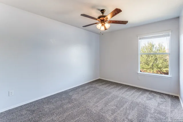 an empty room with a window and a fan