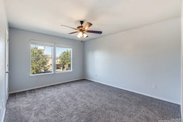 an empty room with windows and chandelier fan