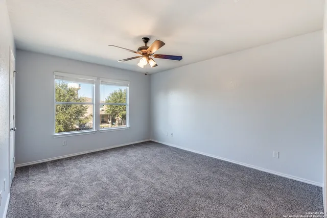 an empty room with windows and chandelier fan
