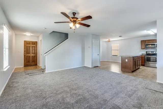 a view of a livingroom with a ceiling fan and kitchen space