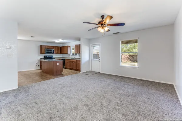 a view of a kitchen with a stove cabinets a ceiling fan and wooden floor