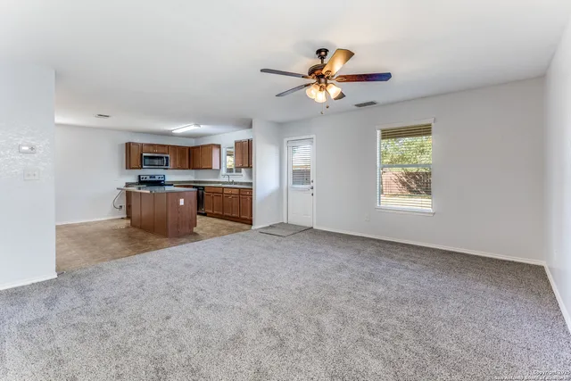 a view of a kitchen with a stove cabinets a ceiling fan and wooden floor