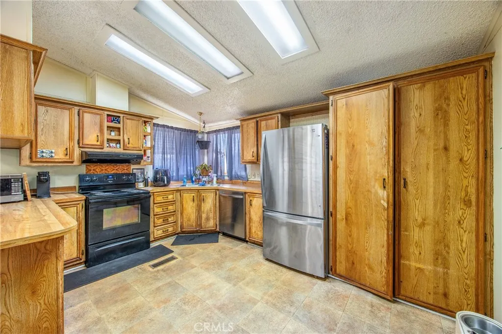 7717 Church Street, Unit 160 Highland, CA 92346 - Photo 12 of 37 a kitchen with a refrigerator a stove top oven a sink and dishwasher