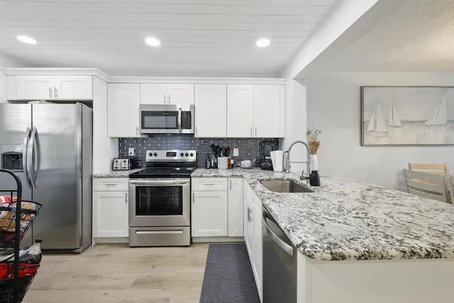 a kitchen with granite countertop a sink stove and refrigerator