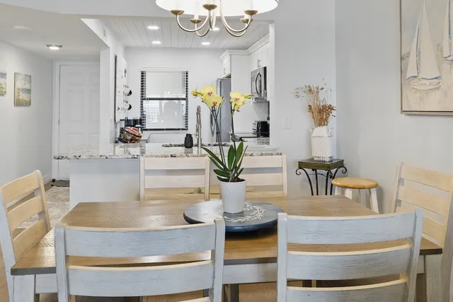 a view of kitchen with stainless steel appliances granite countertop dining table chairs and chandelier