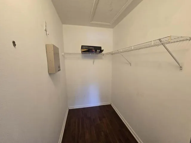 a view of an empty room with wooden floor and closet