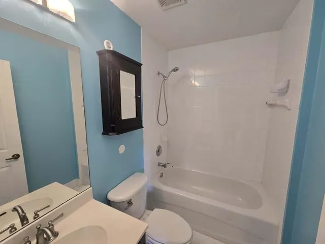 a bathroom with a toilet a sink a mirror a vanity and window