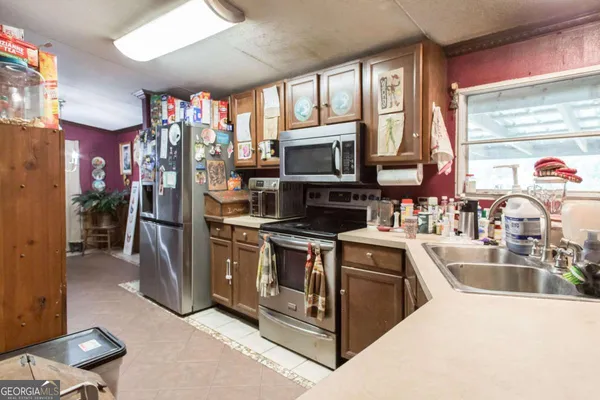 a kitchen with stainless steel appliances granite countertop a stove top oven a sink a refrigerator and a microwave