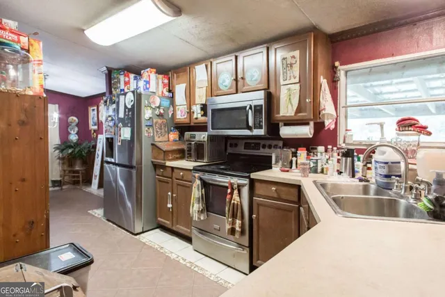 a kitchen with stainless steel appliances granite countertop a stove top oven a sink a refrigerator and a microwave