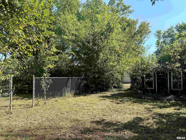 a backyard of a house with large trees and outdoor seating