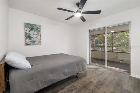 an empty room with wooden floor fan and windows