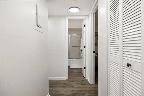 a view of an empty room with wooden floor and closet