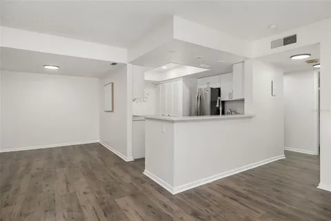 a kitchen with white cabinets stainless steel appliances and wooden floor