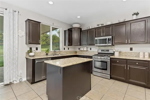 a kitchen with kitchen island granite countertop a sink stove and microwave