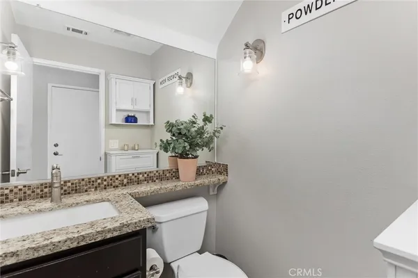 a bathroom with a granite countertop sink and a toilet