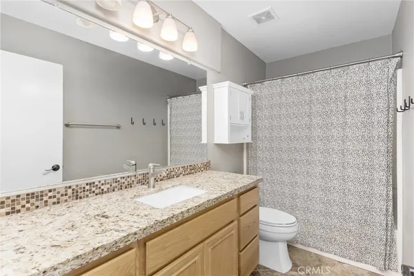 a bathroom with a granite countertop sink a toilet and a shower