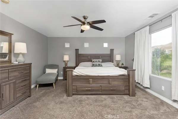 a spacious bedroom with a bed a chandelier and a large window