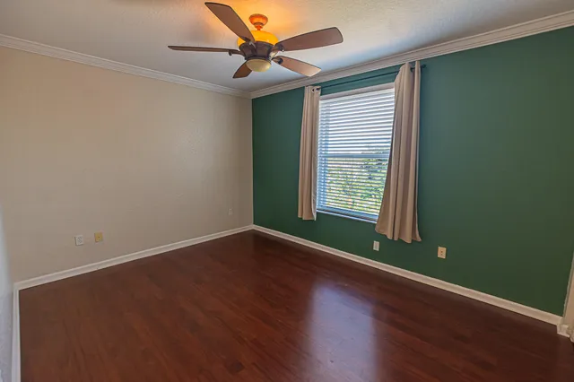 an empty room with wooden floor and windows