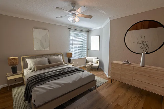 a spacious bedroom with a bed a mirror on dresser and a chandelier