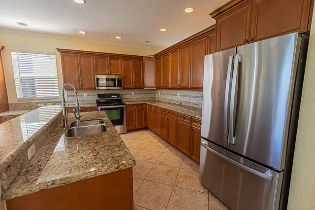 a kitchen with stainless steel appliances granite countertop a refrigerator a stove a sink and a microwave