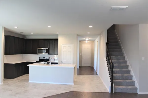 a view of kitchen with stainless steel appliances kitchen island granite countertop a stove a sink and a microwave