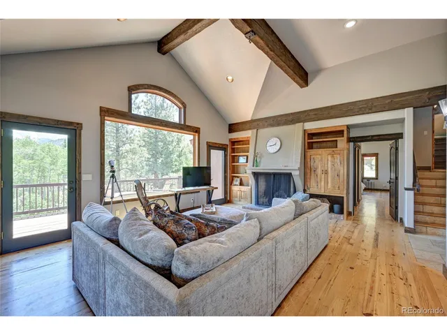 a living room with furniture a flat screen tv and a floor to ceiling window