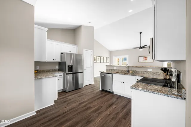 a kitchen with granite countertop a refrigerator stove top oven and sink