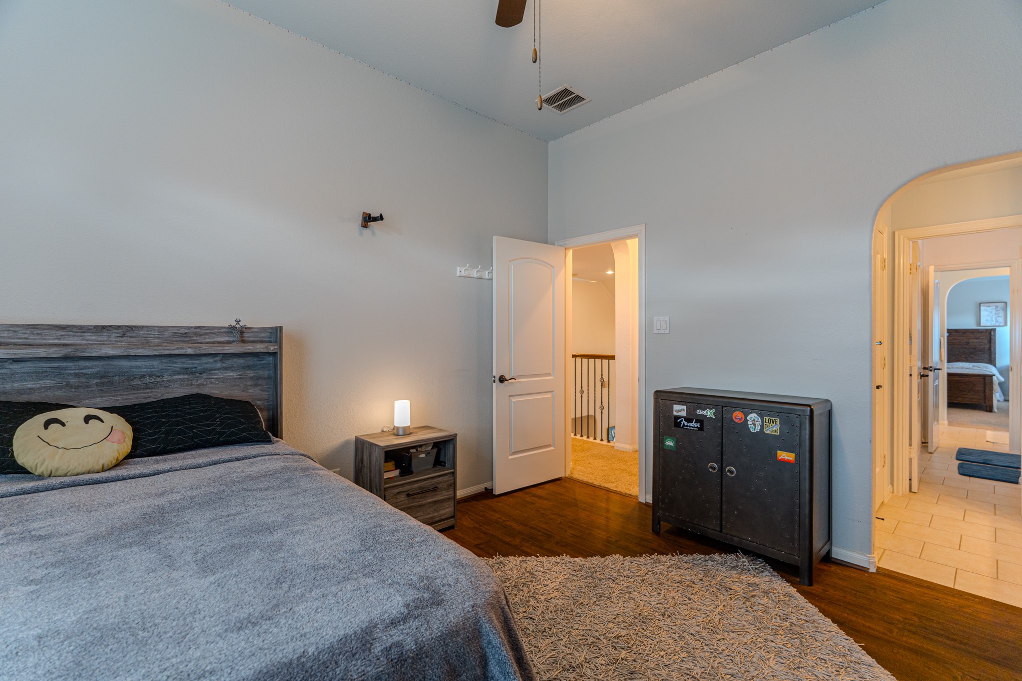 30 Fury Ranch Place The Woodlands, TX 77375 - Photo 38 of 47 This cozy bedroom features a vaulted ceiling with a fan, a large window with blinds, and a blue accent wall. It includes a wooden dresser, a bed with neutral bedding, and a soft area rug on hardwood floors, creating a comfortable and inviting space.