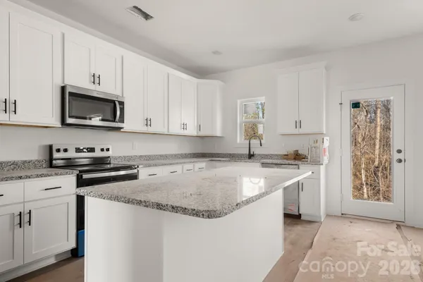 a kitchen with stainless steel appliances granite countertop a stove a sink and a microwave