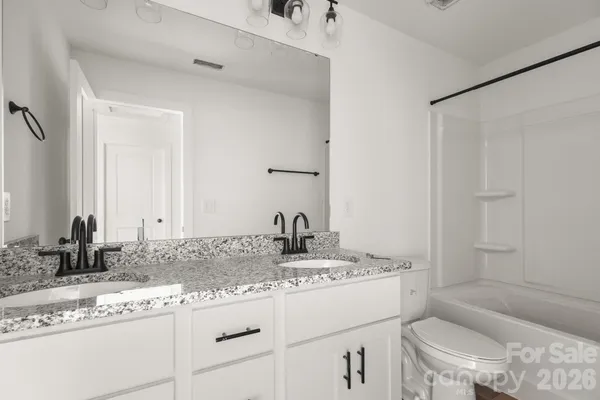 a bathroom with a granite countertop sink mirror vanity and toilet