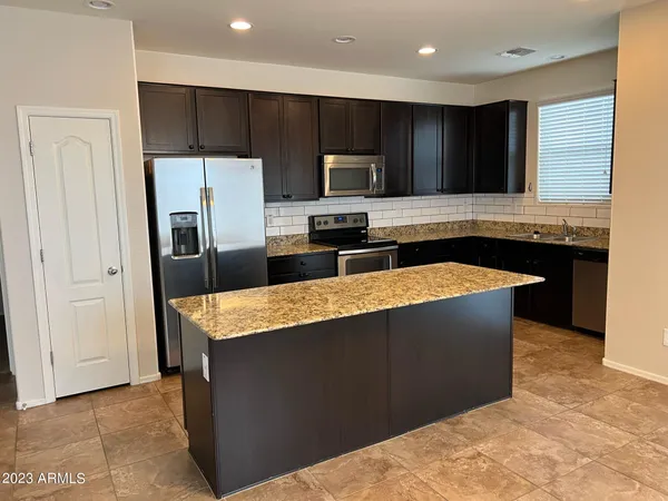 a kitchen with stainless steel appliances granite countertop a stove a refrigerator and a sink with wooden cabinets