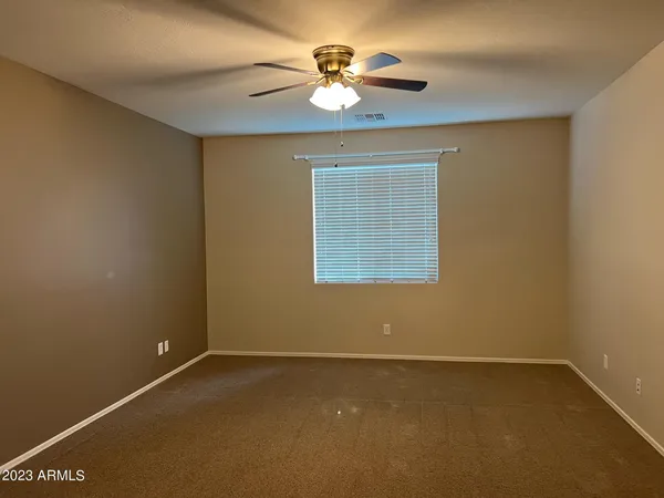 an empty room with a chandelier fan and windows