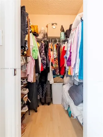 a view of walk in closet with clothes and shoes
