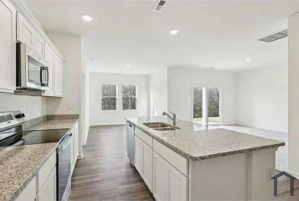 a kitchen with granite countertop stainless steel appliances a sink a stove and a center island