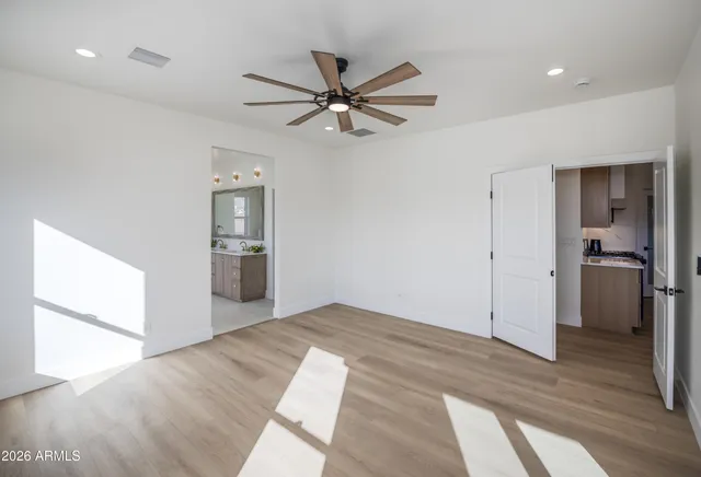 a view of empty room with wooden floor and ceiling fan