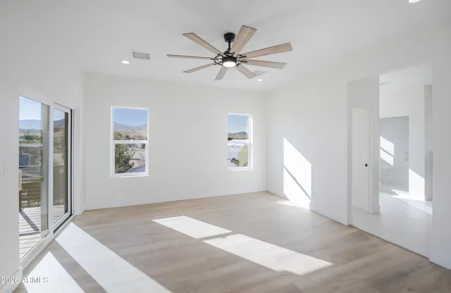 a view of a livingroom with a ceiling fan & windows