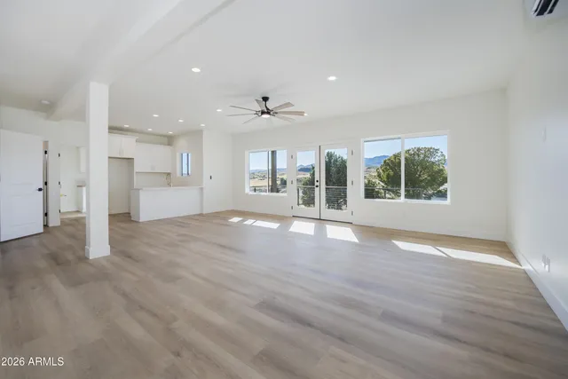 an empty room with wooden floor ceiling fan and window
