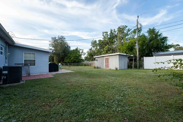 a backyard of a house with plants and large tree