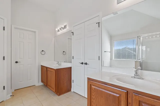 a bathroom with a sink double vanity granite tub shower and mirror